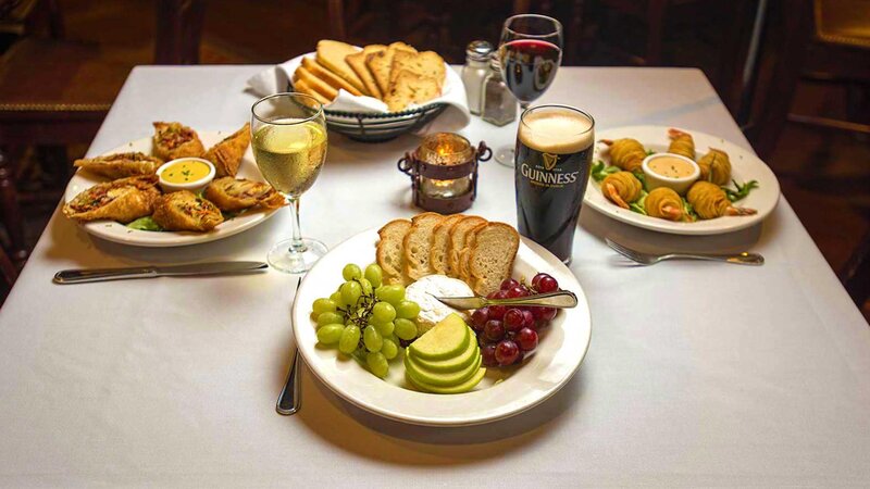Multiple appetizers with focus on brie cheese with apples, grapes and bread appetizer