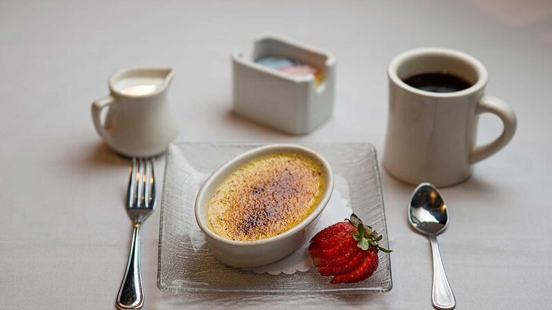 Creme brulee dessert with a strawberry and coffee
